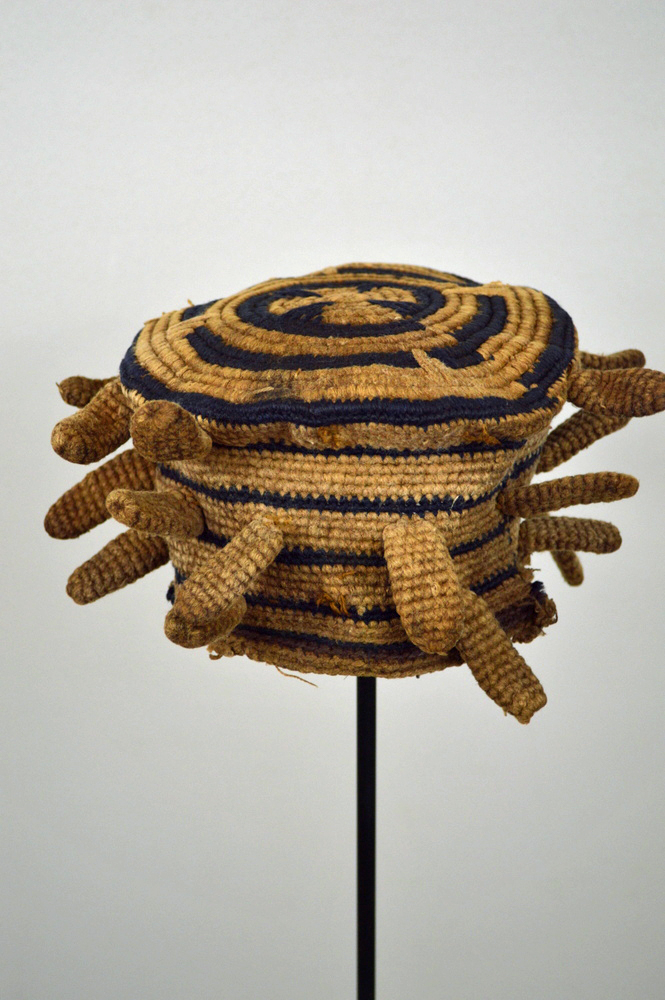 Traditional Craftsmanship Behind Large White and Brown Bamileke Hats